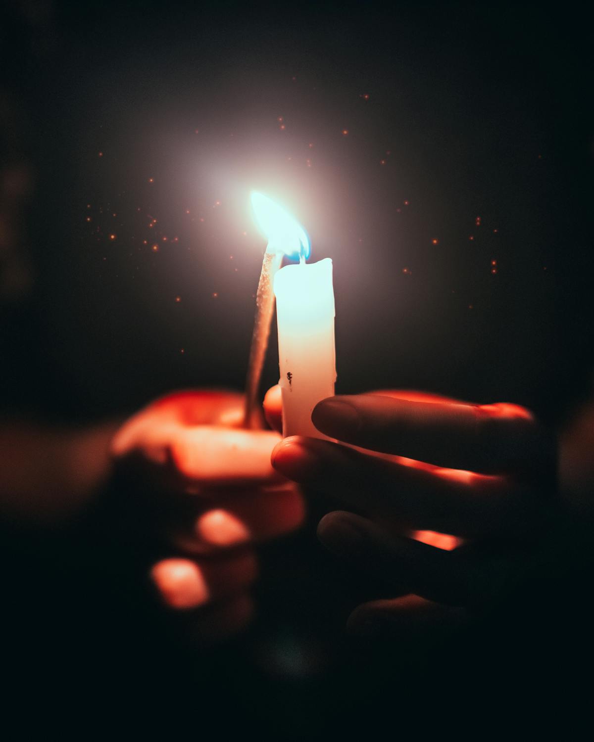 Handen die een brandende kaars vasthouden